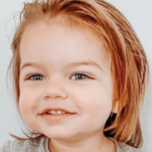 The same toddler, hair smoothed back off the face, smiling