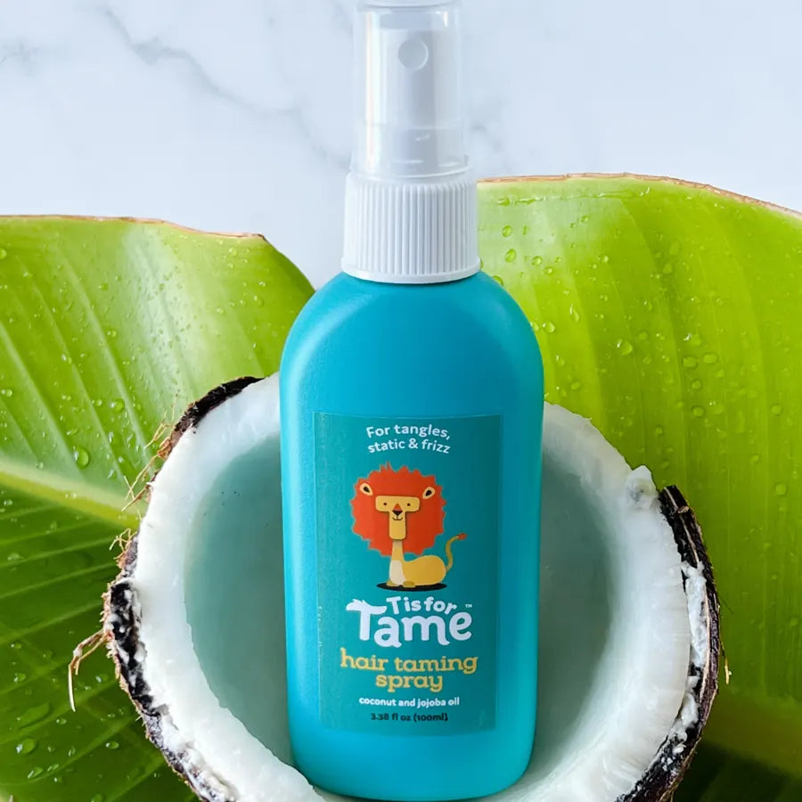 The teal Taming Spray in a coconut shell on a leaf