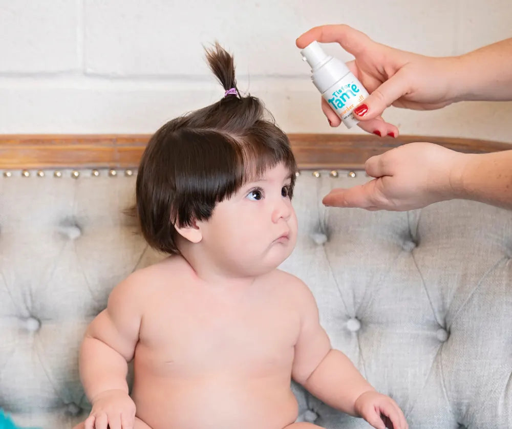 A baby with a tiny top knot getting her hair misted
