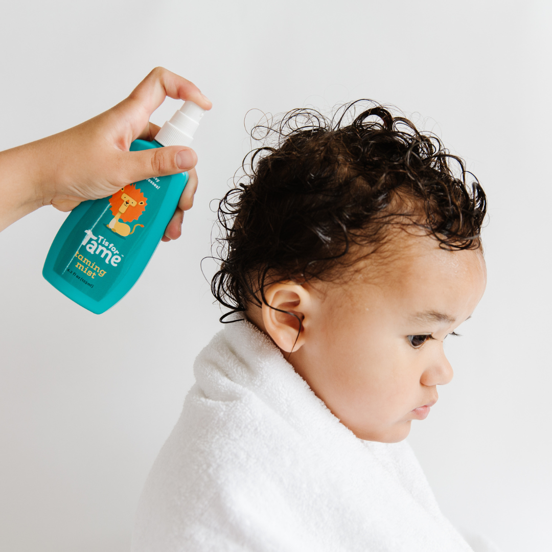A baby’s tangled hair getting sprayed with kids detangling spray