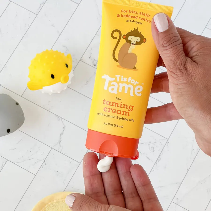 A hand holding a tube of Taming Cream over an open palm with a dab of cream